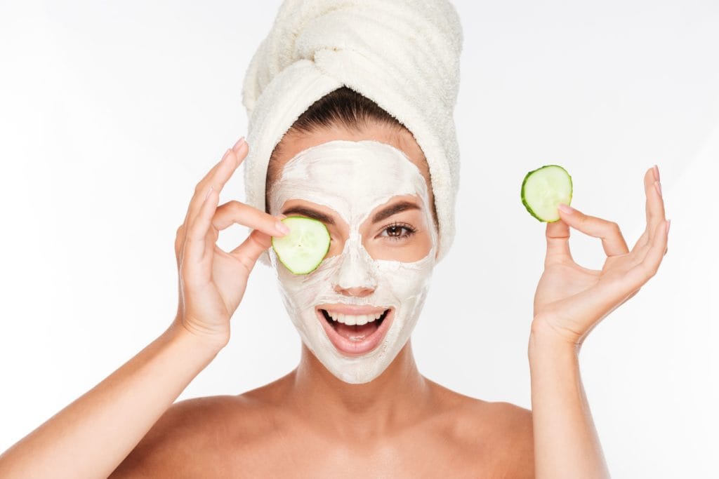 woman with facial mask and cucumber slices in her hands on white background SBI 302779403 3