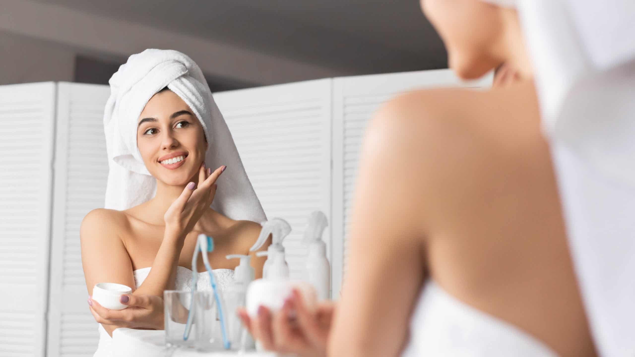 Smiling Millennial Girl Applying Face Cream Moisturizing Skin In Bathroom | gfacemd | Wellesley
